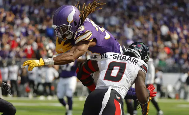 Minnesota Vikings running back Aaron Jones (33) scores on an 8-yard touchdown reception over Houston Texans linebacker Azeez Al-Shaair (0) during the first half of an NFL football game, Sunday, Sept. 22, 2024, in Minneapolis. (AP Photo/Bruce Kluckhohn)