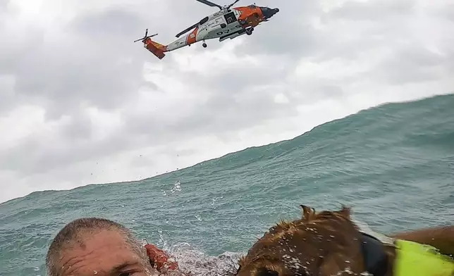 This photo provided by U.S. Coast Guard District Seven (USCGSoutheast) shows a man and his dog being rescued after his sailboat became disabled during Hurricane Helene approximately 25 miles off Sanibel Island, Fla., on Thursday, Sept. 26, 2024. (U.S. Coast Guard District Seven via AP)