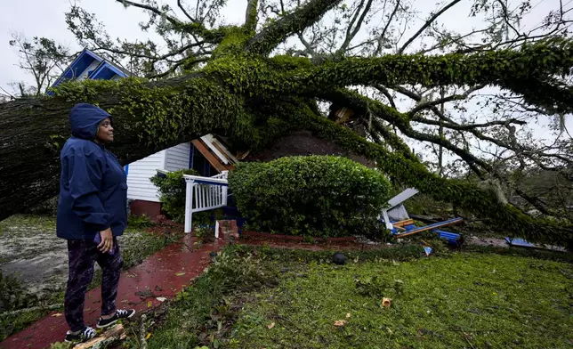 Rhonda Bell looks on after an Oak tree landed on her 100-year-old home after Hurricane Helene moved through, Friday, Sept. 27, 2024, in Valdosta, Ga. (AP Photo/Mike Stewart)