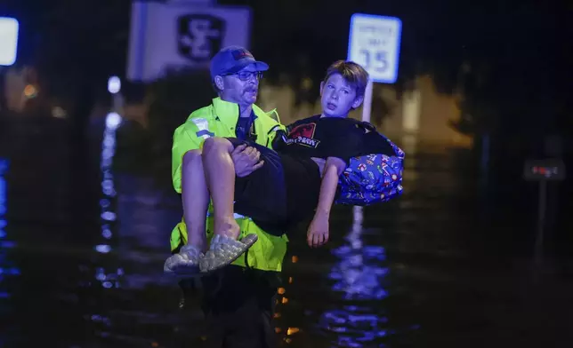 A Citrus County Firefigher carries 11-year- old, Michael Cribbins, while conducting rescues from floodwaters in the aftermath of Hurricane Helene on Friday, Sept. 27, 2024 in Crystal River, Fla. (Luis Santana/Tampa Bay Times via AP)