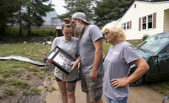 Dustin Bentley, center, kisses his wife Jennifer Bentley, left, after retrieving family photos from their flood-damaged home in the aftermatch of Hurricane Helene as his mother Janet Sams looks on Saturday, Sept. 28, 2024, in Newport, Tenn. (AP Photo/George Walker IV)