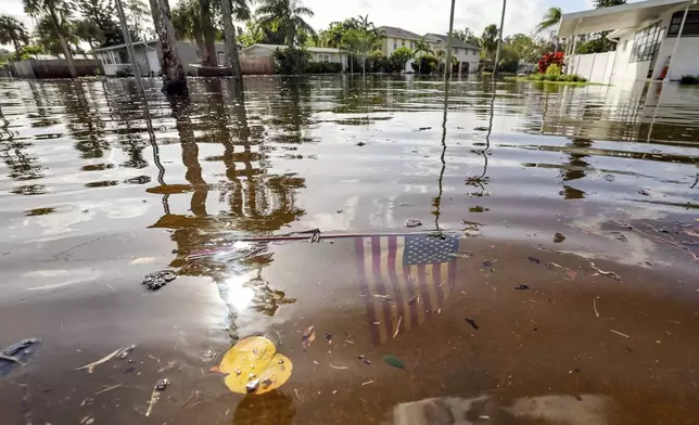 An American flag sits in floodwaters in the aftermath of Hurricane Helene in the Shore Acres neighborhood Friday, Sept. 27, 2024, in St. Petersburg, Fla. (AP Photo/Mike Carlson)