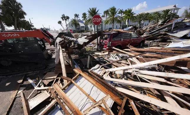 Workers clear debris in the aftermath of Hurricane Helene, in Cedar Key, Fla., Friday, Sept. 27, 2024. (AP Photo/Gerald Herbert)