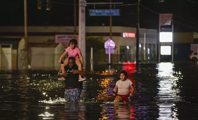 Jamir Lewis wades through floodwaters with his two daughters, Nylah and Aria, in the aftermath of Hurricane Helene on Friday, Sept. 27, 2024 in Crystal River, Fla. (Luis Santana/Tampa Bay Times via AP)