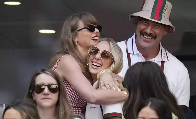 Taylor swift, left, hugs Brittany Mahomes as Travis Kelce looks on during the men's singles final between Jannik Sinner, of Italy, and Taylor Fritz, of the United States, at the U.S. Open tennis championships, Sunday, Sept. 8, 2024, in New York. (AP Photo/Kirsty Wigglesworth)