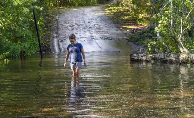 Teresa Elder walks through a flooded Sandy Cove Drive, from Hurricane Helene Friday, Sept. 27, 2024 in Morganton, N.C. (AP Photo/Kathy Kmonicek)