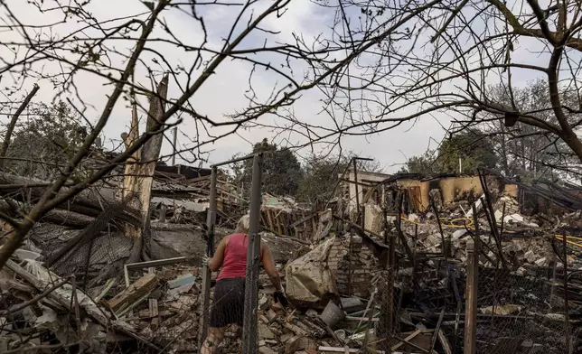 A woman collects her possessions in the yard of a house destroyed after a Russian strike on the residential neighbourhood in Cherkaska Lozova, Kharkiv region, Ukraine, Saturday Aug. 31. 2024. (AP Photo/Yevhen Titov)