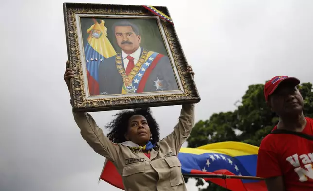 A member of the Bolivarian Militia holds up a painting depicting President Nicolas Maduro during a rally celebrating Maduro's July 28 reelection, in Caracas, Venezuela, Saturday, Sept. 28, 2024. (AP Photo/Cristian Hernandez)