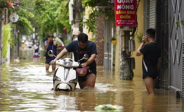 People wade in a flooded street in the aftermath of Typhoon Yagi, in Hanoi, Vietnam on Thursday, Sep. 12, 2024. (AP Photo/Hau Dinh)