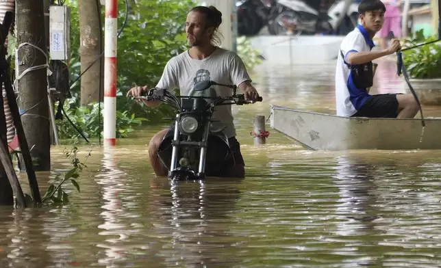 A man pushes his motorbike in a flooded street in the aftermath of Typhoon Yagi, in Hanoi, Vietnam on Thursday, Sept. 12, 2024. (AP Photo/Hau Dinh)