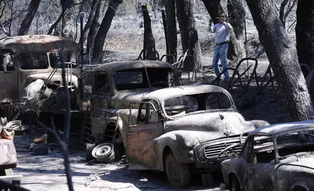 A reporter takes cell phone images of the devastation left behind by the Airport Fire, Wednesday, Sept. 11, 2024, in El Cariso Village, in unincorporated Riverside County, Calif. (AP Photo/Gregory Bull)