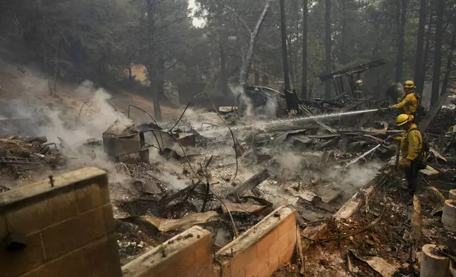 Firefighters hose down hot spots on a fire-ravaged property while battling the Bridge Fire, Wednesday, Sept. 11, 2024, in Wrightwood, Calif. (AP Photo/Eric Thayer)