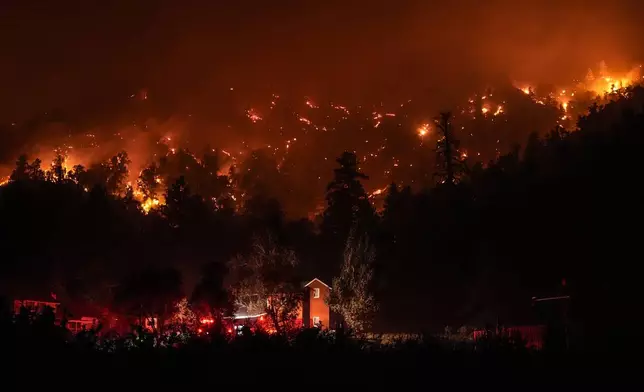 Firetrucks are seen around a building as scorched trees smolder during the Bridge Fire in Wrightwood, Calif., Wednesday, Sept. 11, 2024. (AP Photo/Jae C. Hong)