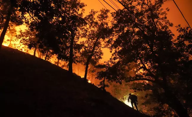 A firefighter is silhouetted against the glow from the Bridge Fire in Wrightwood, Calif., Tuesday, Sept. 10, 2024. (AP Photo/Jae C. Hong)