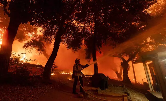 A firefighter battles the Airport Fire, Tuesday, Sept. 10, 2024, in El Cariso, an unincorporated community in Riverside County, Calif. (AP Photo/Etienne Laurent)