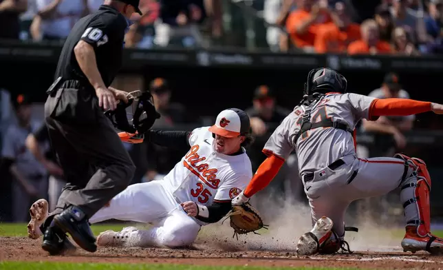 Baltimore Orioles' Adley Rutschman (35) slides into home plate to score ahead of the tag by San Francisco Giants catcher Patrick Bailey (14) during the fourth inning of a baseball game, Thursday, Sept. 19, 2024, in Baltimore. (AP Photo/Stephanie Scarbrough)