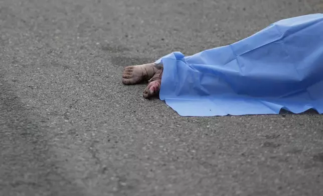 A blue sheet covers a body found lying on the side of a road in Culiacan, Sinaloa state, Mexico, Saturday, Sept. 21, 2024. (AP Photo/Eduardo Verdugo)