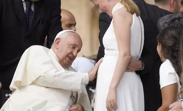 Pope Francis touches the belly of a newly married woman during his weekly general audience in St. Peter's Square, at the Vatican, Wednesday, Sept. 25, 2024. (AP Photo/Gregorio Borgia)