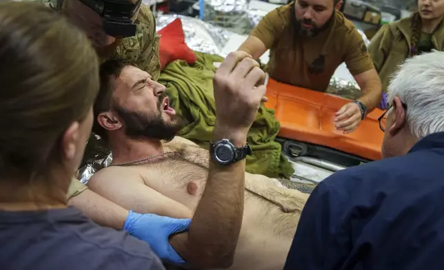 Ukrainian military medics of the Azov brigade move an injured comrade on a stretcher, at the stabilization point near Toretsk, Donetsk region, Ukraine, Tuesday, Sept. 24, 2024. (AP Photo/Evgeniy Maloletka)