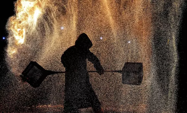 An artist performs a fire kettle show during the Mid-Autumn Festival at a night market in Beijing, Tuesday, Sept. 17, 2024. (AP Photo/Andy Wong)