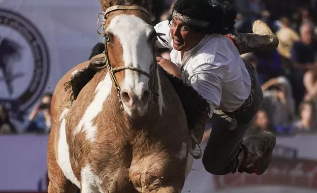 A man wearing traditional clothing performs acrobatics on a horse during Independence Day celebrations in Santiago, Chile, Tuesday, Sept. 17, 2024. (AP Photo/Matias Basualdo)