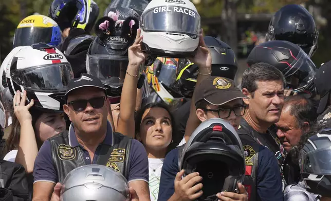 Faithful hold up their helmets to be blessed during the IX Pilgrimage of the Blessing of Helmets that draws tens of thousands at the Roman Catholic holy shrine of Fatima, in Fatima, Portugal, Sunday, Sept. 22, 2024. (AP Photo/Ana Brigida)