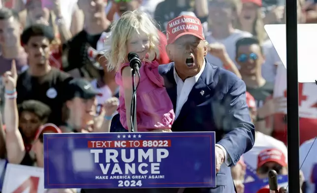 Republican presidential nominee former President Donald Trump holds his granddaughter Carolina Trump as he speaks at a campaign event at Wilmington International Airport in Wilmington, N.C., Saturday, Sept. 21, 2024. (AP Photo/Chris Seward)