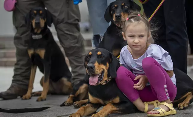 A girl with her family and hunting dogs attends in the traditional Nations' Fair in Vilnius, Lithuania, Sunday, Sept. 15, 2024. (AP Photo/Mindaugas Kulbis)