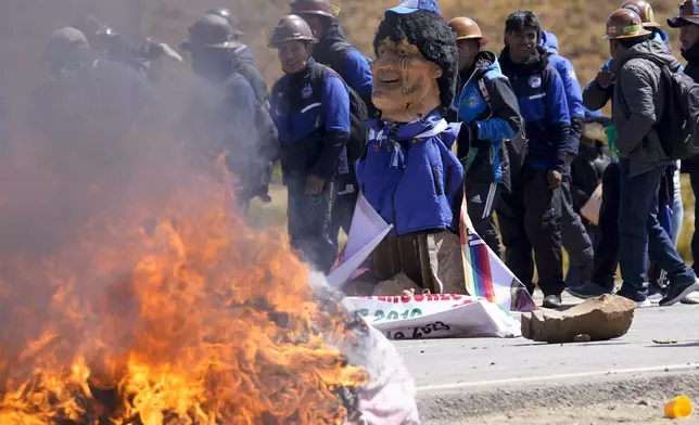 An effigy of former President Evo Morales burns on a road in Vila Vila, Bolivia, to block Morales supporters who are marching to the capital to protest the government of current President Luis Arce in an escalation of a political dispute between the two politicians, Tuesday, Sept. 17, 2024. (AP Photo/Juan Karita)