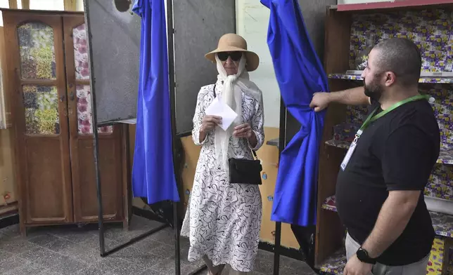 A voter prepares to cast her ballot inside a polling station during the presidential elections, Saturday, Sept. 7, 2024, in Algiers, Algeria. (AP Photo/Fateh Guidoum)