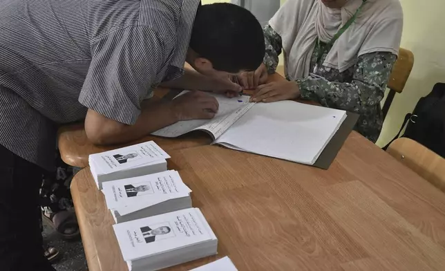 A voter prepares to cast his ballot inside a polling station during the presidential election, Saturday, Sept. 7, 2024, in Algiers, Algeria. (AP Photo/Fateh Guidoum)