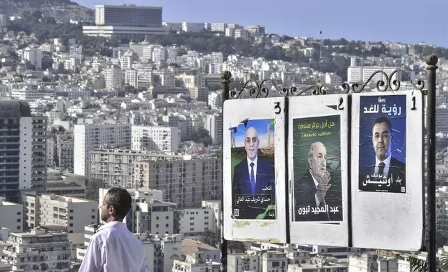 A man walks past electoral banners of presidential candidate, including President Abdelmadjid Tebboune, center, Tuesday, Aug. 27, 2024, in Algiers, Algeria. (AP Photo/Fateh Guidoum)