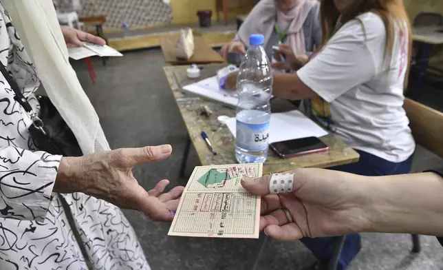 A voter prepares to cast her ballot inside a polling station during the presidential elections, Saturday, Sept. 7, 2024, in Algiers, Algeria. (AP Photo/Fateh Guidoum)