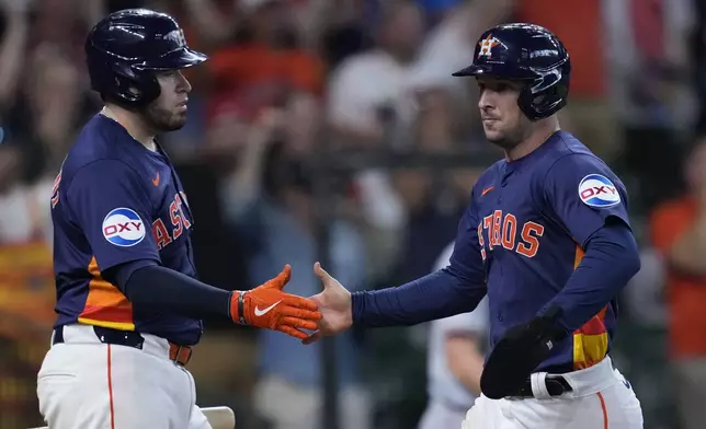 Houston Astros' Alex Bregman, right, slaps hands with Victor Caratini, left, after scoring during the eighth inning of a baseball game against the Los Angeles Angels, Sunday, Sept. 22, 2024, in Houston. (AP Photo/Kevin M. Cox)