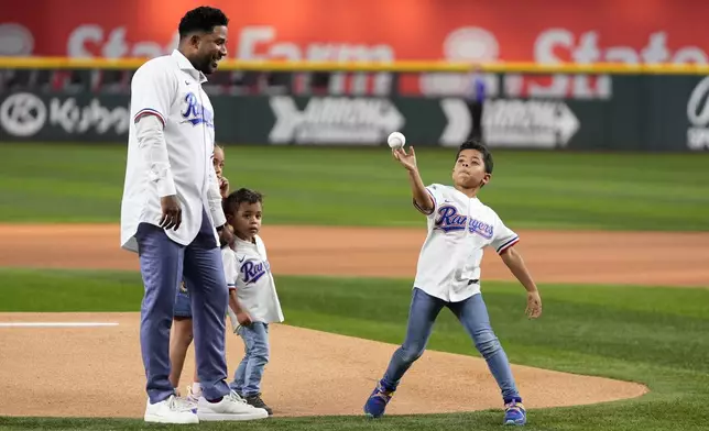 Texas Rangers former player Elvis Andrus, left, who announced his retirement earlier Friday, stands with his daughter Lucia, left rear, and Michael, center, as Elvis Jr., right, throws out the ceremonial first pitch before a baseball game between the Los Angeles Angels and Rangers, Friday, Sept. 6, 2024, in Arlington, Texas. (AP Photo/Tony Gutierrez)