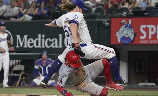 Los Angeles Angels' Zach Neto, bottom, slides into home plate against Texas Rangers pitcher Andrew Chafin, top, to score on a wild pitch during the sixth inning of a baseball game Saturday, Sept. 7, 2024, in Arlington, Texas. (AP Photo/LM Otero)