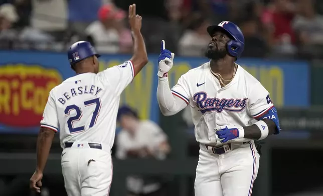 Texas Rangers' Adolis Garcia, right, and third base coach Tony Beasley (27) celebrate Garcia's three-run home run against the Los Angeles Angels in the first inning of a baseball game Thursday, Sept. 5, 2024, in Arlington, Texas. (AP Photo/Tony Gutierrez)