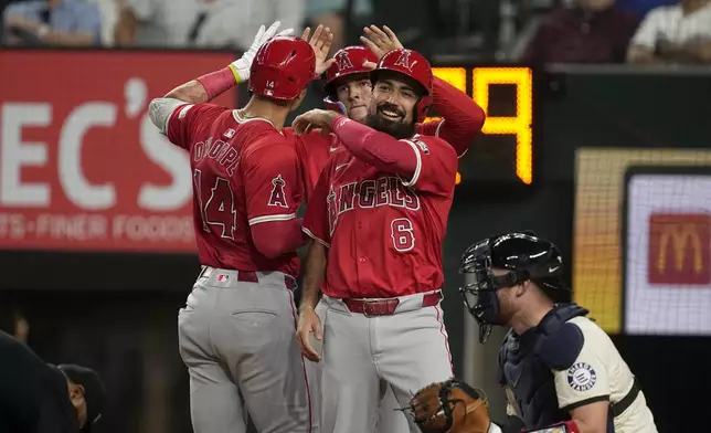 Los Angeles Angels' Anthony Rendon (6), Logan O'Hoppe (14) and Mickey Moniak, center back, celebrate after Hoppe's three-run home run scored them as Texas Rangers catcher Carson Kelly, right, kneels by the plate in the sixth inning of a baseball game Friday, Sept. 6, 2024, in Arlington, Texas. (AP Photo/Tony Gutierrez)