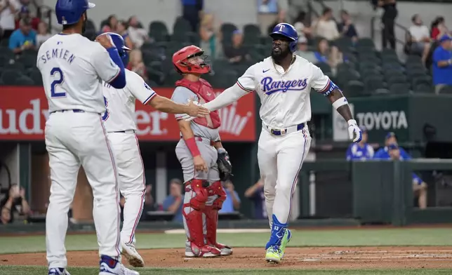 Texas Rangers' Adolis Garcia, right, jogs past Los Angeles Angels catcher Matt Thaiss, center rear, as he celebrates with Marcus Semien (2) and Josh Smith, second from left, who both scored on Garcia's three-run home run in the first inning of a baseball game Thursday, Sept. 5, 2024, in Arlington, Texas. (AP Photo/Tony Gutierrez)