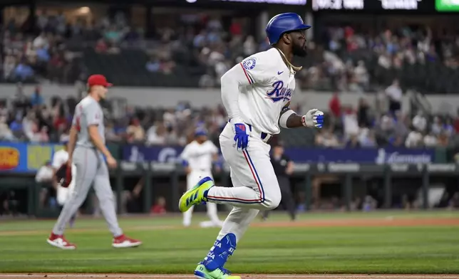 Texas Rangers' Adolis Garcia, front, rounds the bases after hitting a three-run home run off a pitch from Los Angeles Angels starting pitcher Jack Kochanowicz, left rear, in the first inning of a baseball game Thursday, Sept. 5, 2024, in Arlington, Texas. (AP Photo/Tony Gutierrez)