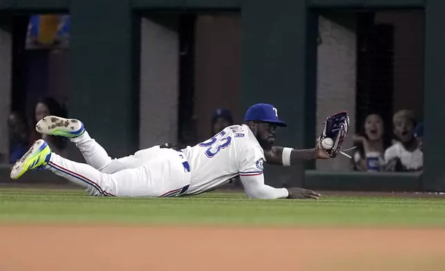 Texas Rangers right fielder Adolis Garcia makes a sliding stop on a single by Los Angeles Angels' Brandon Drury in the seventh inning of a baseball game Thursday, Sept. 5, 2024, in Arlington, Texas. (AP Photo/Tony Gutierrez)