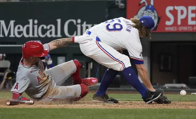 Los Angeles Angels' Zach Neto, left, slides into home plate against Texas Rangers pitcher Andrew Chafin (59) to score on a wild pitch during the sixth inning of a baseball game Saturday, Sept. 7, 2024, in Arlington, Texas. (AP Photo/LM Otero)