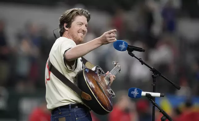 Recording artist and cousin to Texas Rangers manager Bruce Bochy, Jake Troth, waves to the Rangers dugout after singing the national anthem before a baseball game against the Los Angeles Angels Friday, Sept. 6, 2024, in Arlington, Texas. (AP Photo/Tony Gutierrez)