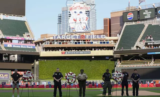 First responders and military members stand with wreaths in remembrance of 9/11 before a baseball game between the Los Angeles Angels and Minnesota Twins, Wednesday, Sept. 11, 2024, in Minneapolis. (AP Photo/Abbie Parr)