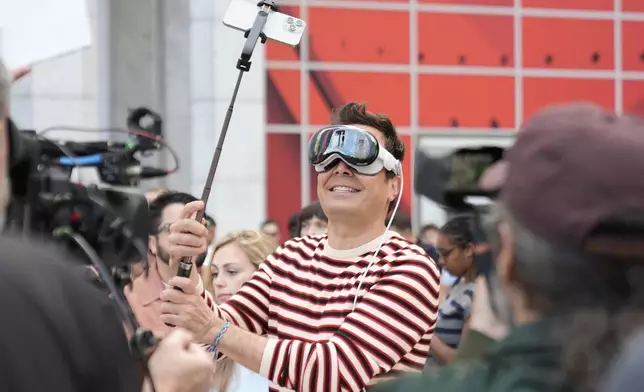 Jimmy Fallon stands with an iPhone outside of the Apple Fifth Avenue store for the release of the Apple iPhone 16, Friday, Sept. 20, 2024, in New York. (AP Photo/Pamela Smith)