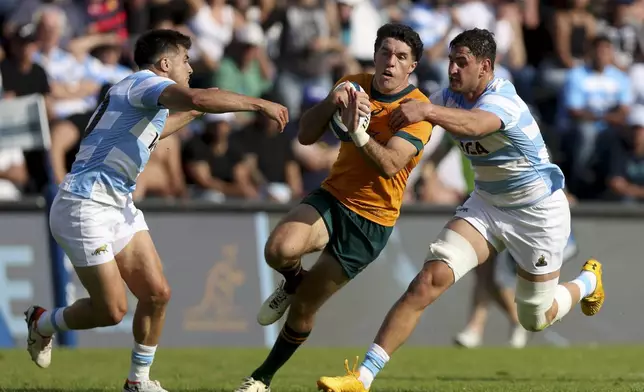 Australia's Ben Donaldson, center, is tackled by Argentina's Los Pumas Juan Martin Gonzalez during a rugby championship test match in Santa Fe, Argentina, Saturday, Sept. 7, 2024. (AP Photo/Mateo Occhi)