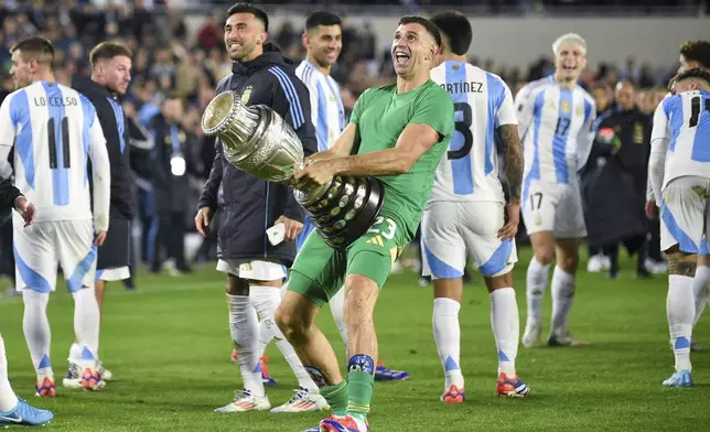 Argentina's goalkeeper Emiliano Martinez holds the 2024 Copa America trophy after a qualifying soccer match for the FIFA World Cup 2026 against Chile in Buenos Aires, Argentina, Thursday, Sept. 5, 2024. (AP Photo/Gustavo Garello)