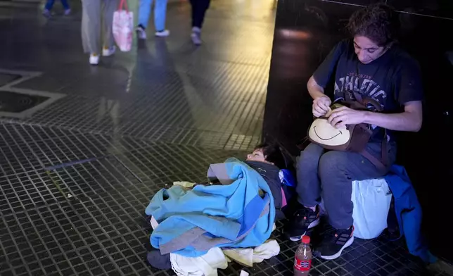 Cintia Barros' son Alessandre sleeps on the ground as she begs on a street corner sidewalk in downtown Buenos Aires, Argentina, Tuesday, Sept. 3, 2024. (AP Photo/Natacha Pisarenko)