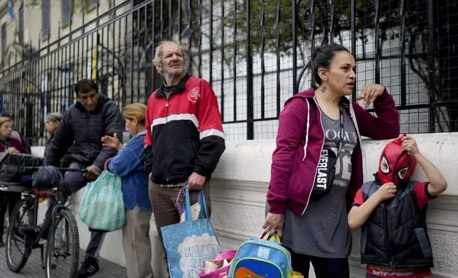 Sofia Gonzalez Figueroa and her son Emanuel stand in line outside a soup kitchen for a free, hot meal, where they walked to from home on the outskirts of Buenos Aires, Argentina, Monday, Sept. 9, 2024. (AP Photo/Natacha Pisarenko)