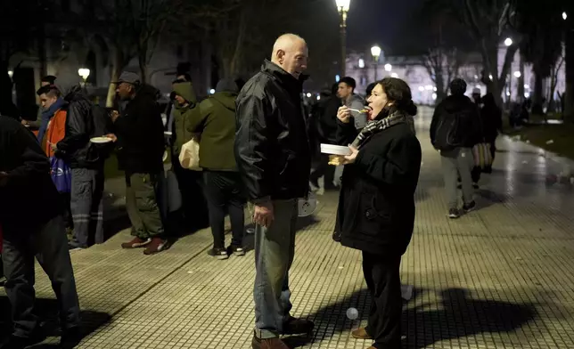 Debora Paola Galluccio eats her one meal of the day from a community kitchen next to her partner Marcelo Díaz in Buenos Aires, Argentina, Monday, Sept. 9, 2024. (AP Photo/Natacha Pisarenko)